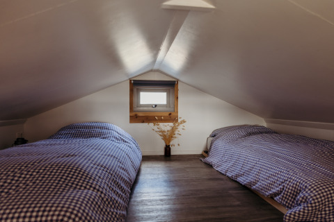 Cozy attic room with two single beds and checkered bedding in Rescue cottage at Duynpark Het Zwanenwater.