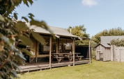 Tente safari Wood Lodge au Duynpark Het Zwanenwater, Pays-Bas, avec tables de pique-nique et verdure.