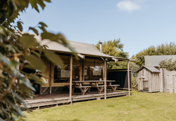 Tente safari Wood Lodge au Duynpark Het Zwanenwater, Pays-Bas, avec tables de pique-nique et verdure.
