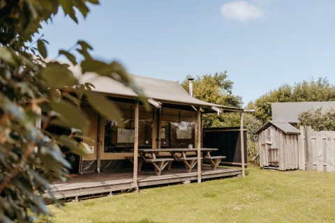 Tienda tipo safari Wood Lodge en Duynpark Het Zwanenwater, Países Bajos, con mesa y zona verde.
