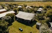 Vista aérea de la tienda safari Wood Lodge en Duynpark Het Zwanenwater, Países Bajos, rodeada de naturaleza.
