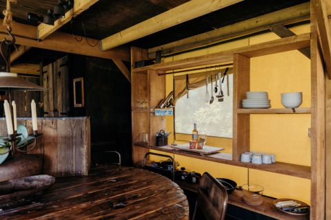 Cuisine chaleureuse sous tente safari au Wood Lodge, Duynpark Het Zwanenwater, Pays-Bas, avec étagères en bois.