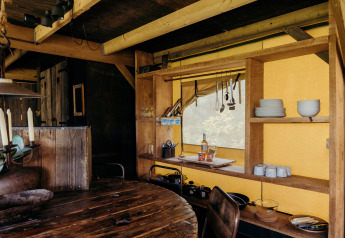 Cozy safari tent kitchen at Wood Lodge, Duynpark Het Zwanenwater, Netherlands, with rustic wood shelves.