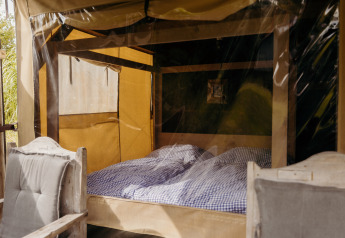 Interior de la tienda safari Wood Lodge en Duynpark Het Zwanenwater, Países Bajos, con cama doble.