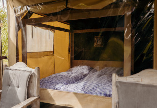 Interior de la tienda safari Wood Lodge en Duynpark Het Zwanenwater, Países Bajos, con cama doble.