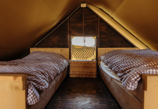 Dos camas individuales con ropa de cama a cuadros en una acogedora tienda safari en Duynpark Het Zwanenwater, Países Bajos.