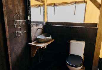 Bagno in tenda safari Wood Lodge, Duynpark Het Zwanenwater, Paesi Bassi, con toilette e lavabo in pietra.
