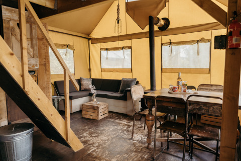 Vue intérieure d'une tente safari Beach Lodge avec mobilier rustique au Duynpark Het Zwanenwater, aux Pays-Bas.