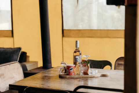Vino, Pringles y aperitivos sobre una mesa en la tienda safari Beach Lodge de Duynpark Het Zwanenwater, Países Bajos.