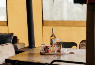 Vino, Pringles y aperitivos sobre una mesa en la tienda safari Beach Lodge de Duynpark Het Zwanenwater, Países Bajos.