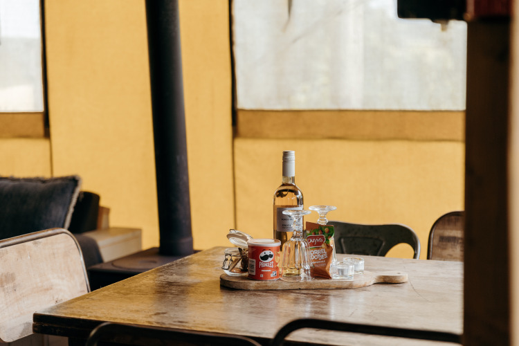 Wijn, Pringles en snacks op tafel in de Beach Lodge safaritent bij Duynpark Het Zwanenwater, Nederland.