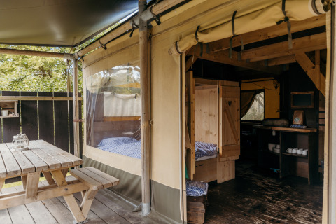 Safari tent setup at Beach Lodge, Duynpark Het Zwanenwater, Netherlands, featuring cozy wooden furniture.