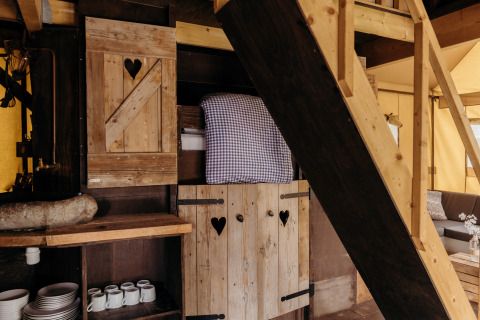 Interior de la tienda safari Beach Lodge en Duynpark Het Zwanenwater, Países Bajos, con muebles de madera y cama.