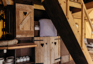 Interior de la tienda safari Beach Lodge en Duynpark Het Zwanenwater, Países Bajos, con muebles de madera y cama.