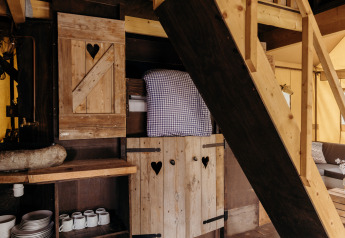 Intérieur de la tente safari Beach Lodge à Duynpark Het Zwanenwater, Pays-Bas, avec mobilier en bois et lit.
