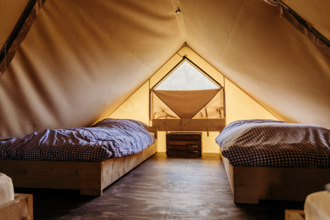 Interior de una tienda safari en Beach Lodge, Duynpark Het Zwanenwater, Países Bajos, con dos camas.