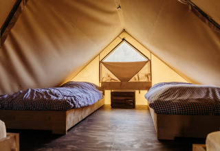 Interior de una tienda safari en Beach Lodge, Duynpark Het Zwanenwater, Países Bajos, con dos camas.