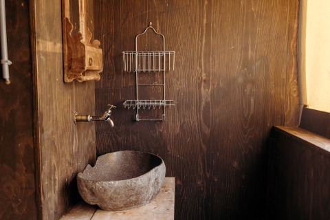 Baño rústico con lavabo de piedra, grifo de pared y estante en Beach Lodge, Duynpark Het Zwanenwater.