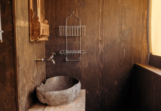 Baño rústico con lavabo de piedra, grifo de pared y estante en Beach Lodge, Duynpark Het Zwanenwater.