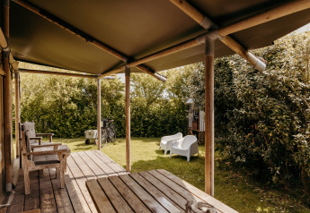 Terrazza all'aperto con mobili in legno presso la tenda safari Beach Lodge a Duynpark Het Zwanenwater, Paesi Bassi.