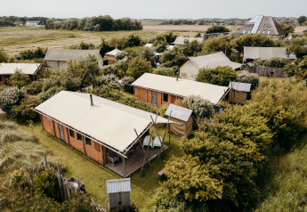 Aerial view of safari tents at Duynlodge in Duynpark Het Zwanenwater, surrounded by greenery and fields.