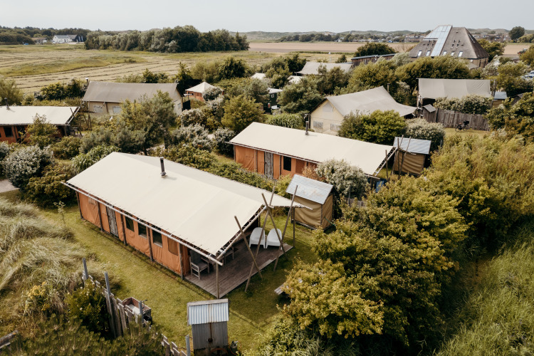 Vista aérea de tiendas safari en Duynlodge, Duynpark Het Zwanenwater, rodeadas de vegetación y campos.