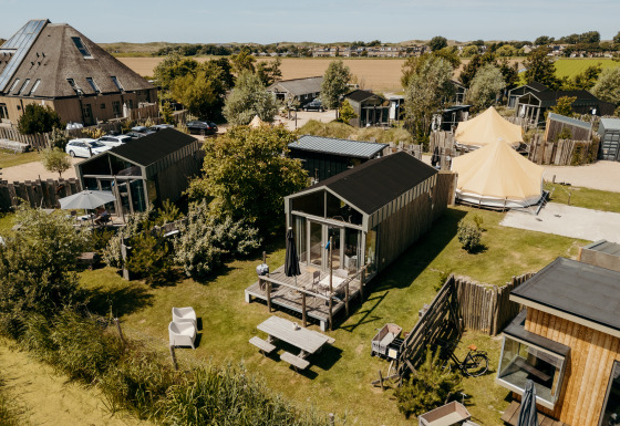 Aerial view of Rescue cottage, a tiny house with a patio and garden, surrounded by similar small homes.
