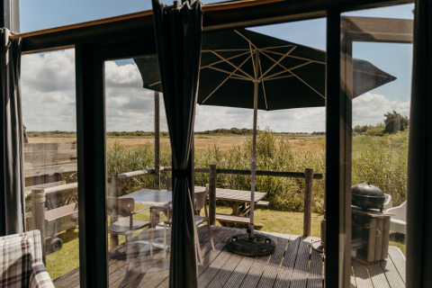 Udsigt fra Rescue cottage ved Duynpark Het Zwanenwater, Holland, med terrasse, bord og parasol.