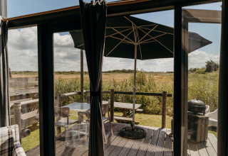 Udsigt fra Rescue cottage ved Duynpark Het Zwanenwater, Holland, med terrasse, bord og parasol.