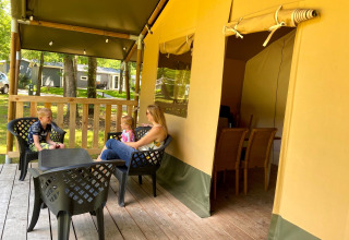 Familie entspannt sich auf der Terrasse eines Glamping-Zeltes im Vakantiepark Bonte Vlucht, Utrecht.