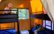 Two children relax on bunk beds inside a tent with orange walls at Vakantiepark Bonte Vlucht, Utrecht.