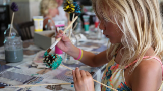 Una bambina dipinge una pigna durante un’attività creativa al Vakantiepark Bonte Vlucht nei Paesi Bassi.