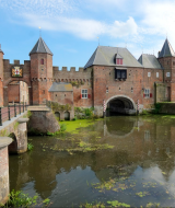 Historisk borg med tårne og voldgrav i nærheden af Doorn, Utrecht, Holland, under en blå himmel.
