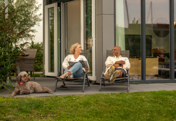 Koppel ontspant buiten tiny house Knilles met hond bij Tusken de Marren, Nederland.