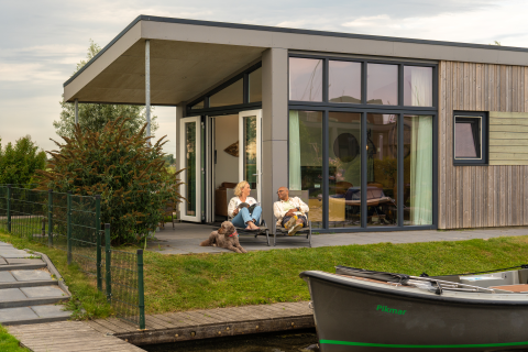 Stel ontspant op het terras van Knilles Luxe tiny house bij Tusken de Marren, Nederland, met hond.