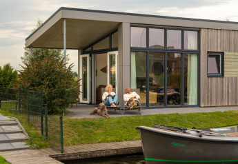 Koppel ontspant op het terras van Knilles Luxe tiny house bij Tusken de Marren, Nederland, met hond.