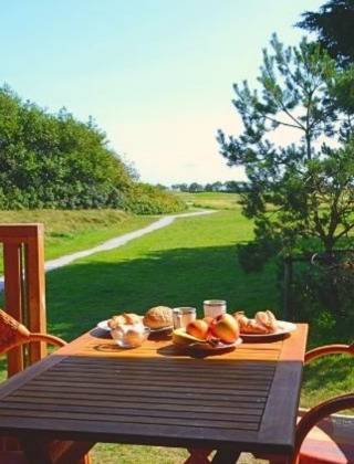 Udendørs spisebord med morgenmad og udsigt til grønne marker i Parc Koudenburg, Friesland, Holland.