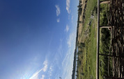 Blick aus dem Tiny House im Holiday Park Eigen Wijze, Niederlande, auf grüne Felder und blauen Himmel.
