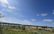 Udsigt fra en lille hytte ved Holiday park Eigen Wijze i Holland med grønne marker og en blå himmel.