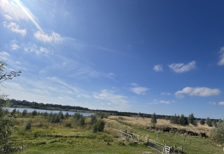 Udsigt fra en lille hytte ved Holiday park Eigen Wijze i Holland med grønne marker og en blå himmel.