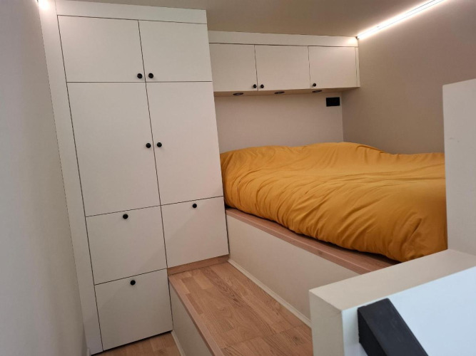 Dormitorio compacto moderno con armarios blancos y ropa de cama amarilla en tiny house en Holiday park Eigen Wijze.