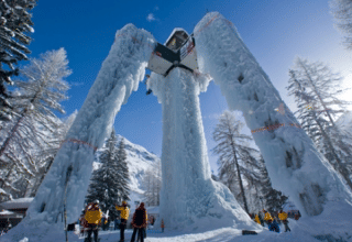 Personas observan una enorme estructura de hielo y góndola en Les Chalets Huttopia Champagny en Vanoise, Francia.
