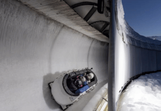 Personer i en bobslæde kører ned ad en isbane ved Les Chalets Huttopia Champagny en Vanoise, Frankrig.