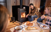 Family enjoys breakfast around a wood stove in a cabin at Les Chalets Huttopia Champagny en Vanoise.