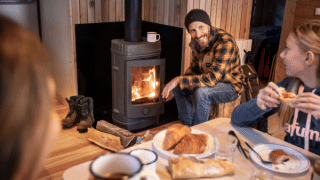 Famille prenant le petit-déjeuner près d’un poêle à bois dans un chalet à Les Chalets Huttopia Champagny en Vanoise.