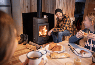 Gezin ontbijt samen bij een houtkachel in een chalet bij Les Chalets Huttopia Champagny en Vanoise.
