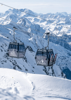 Deux cabines de télécabine à La Plagne entourées de sommets alpins enneigés près de Champagny-en-Vanoise, France.
