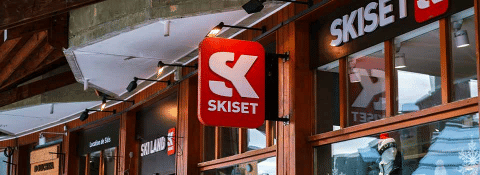 Entrance to a Skiset store at Les Chalets Huttopia Champagny en Vanoise, shown with wood facades and signage.