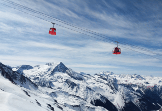 Zwei rote Seilbahnen fahren über verschneite Alpengipfel in Champagny en Vanoise, Auvergne-Rhône-Alpes.