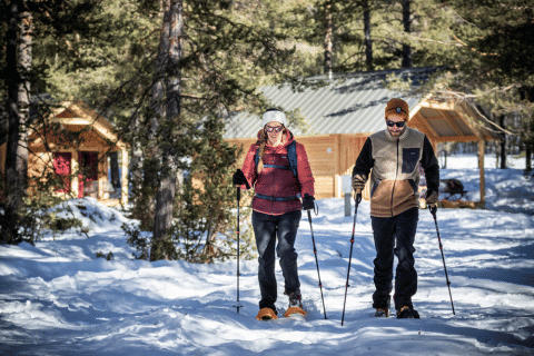 Deux personnes font de la raquette devant un chalet en bois à Champagny en Vanoise, France.